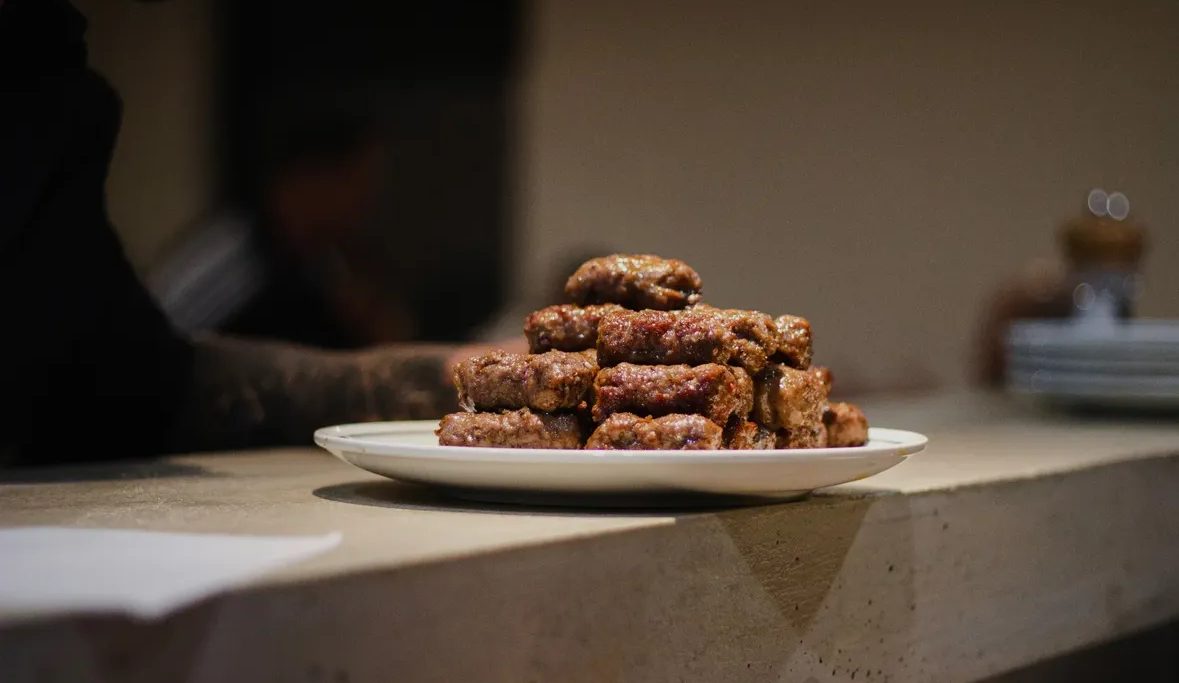 A plate of ćevapi stacked at the kitchen pass