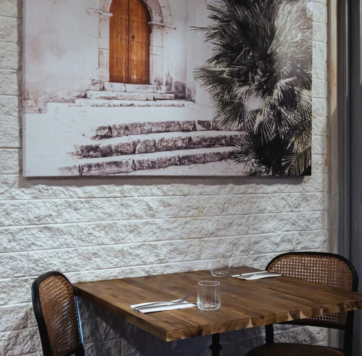 A corner table set beneath framed artwork on a stone wall